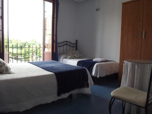 a room with two beds and a chair and a window at Pensión Sandoval by gaiarooms in León