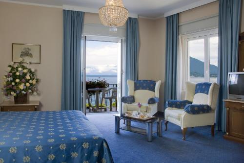 um quarto com uma cama e 2 cadeiras e uma televisão em Hotel Milan Speranza Au Lac em Stresa