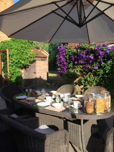 a table with an umbrella on a patio at Lime Trees Farm in Bicester