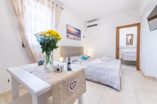 a bedroom with a bed and a table with a vase of flowers at Monolocale Garden in Taviano