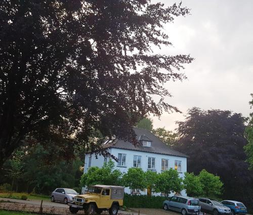 a yellow truck parked in front of a white house at Hotel Au Nom De Dieu in Dilsen-Stokkem