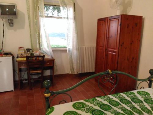 a bedroom with a bed and a desk and a window at Agriturismo Uliveto Gretacci in Montemerano