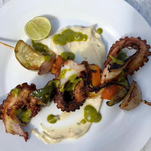 a plate of food with meat and vegetables with a lime at Zanzistar Lodge in Jambiani
