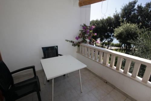 a white table and chairs on a balcony with flowers at Apartments Elia in Mandre