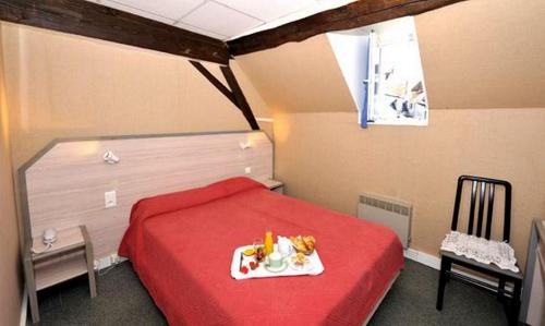 a bedroom with a red bed with a tray on it at Le Compostelle in Vézelay