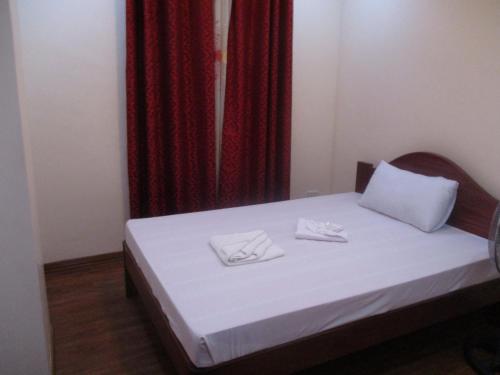 a bedroom with a bed with white sheets and red curtains at WMV Hotel & Restaurant in Infanta