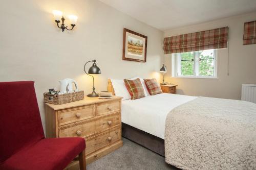 a bedroom with a bed and a red chair at The Conigre in Melksham