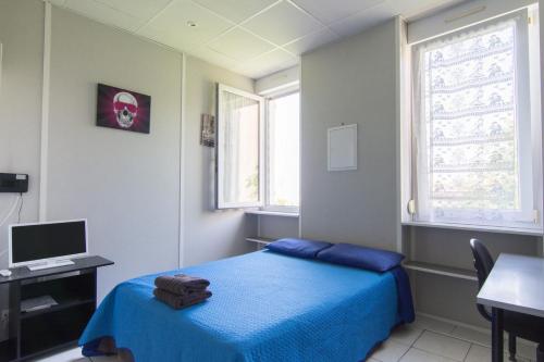 een slaapkamer met een blauw bed, een bureau en een raam bij Résidence Carpe Diem in Marseille