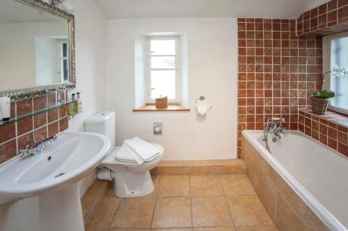a bathroom with a tub and a toilet and a sink at The Conigre in Melksham
