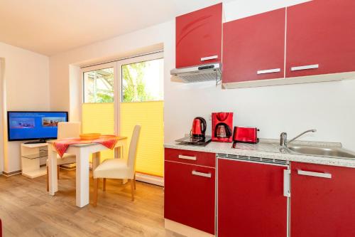 ゲーレンにあるVilla Mia Nr 1 mit Terrasse EG 1 Raum Wohnungのキッチン(赤いキャビネット、デスク、テーブル付)