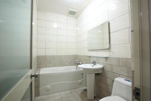 a bathroom with a tub and a sink and a toilet at Long Shan Hotel in Jiaoxi