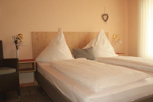 a bedroom with a white bed with white sheets and pillows at Weingut-Brennerei-Gästehaus Emil Dauns in Reil