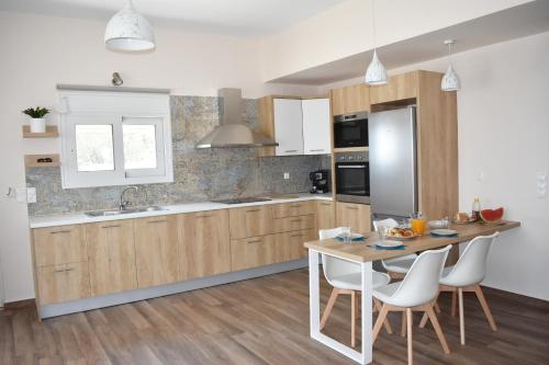 una cucina con tavolo e sedie e una cucina con armadietti bianchi di Sun & Sea Apartments Plakias a Plakiás