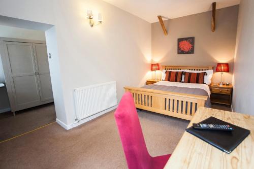 a bedroom with a bed and a desk with a pink chair at The Conigre in Melksham