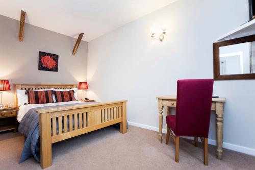 a bedroom with a bed and a desk and a chair at The Conigre in Melksham