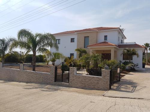 a white house with a fence and palm trees at Nayia Paradise Villa! Best Villa in Cyprus in Paphos City