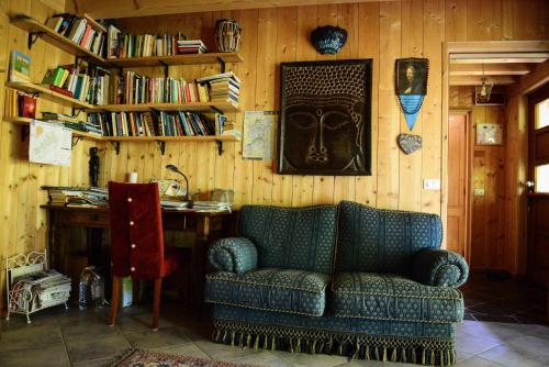a living room with a couch and a desk with books at BioAgriturismo Vegan Campo di Cielo in Cesiomaggiore