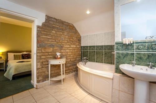 a bathroom with a bath tub and a sink at The Conigre in Melksham