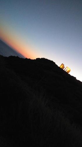 a hill with the sun setting in the background at me gusta suite by the sea in Anavissos