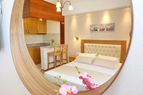 a bedroom with a bed and a kitchen in a mirror at Kastoria Hotel Apartments in Hanioti