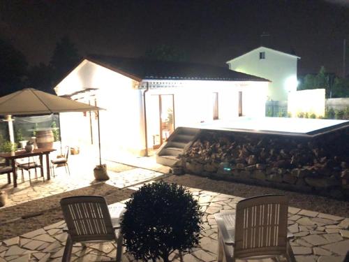a patio at night with two chairs and an umbrella at Il Giardino Di Epicuro in Rocca San Giovanni