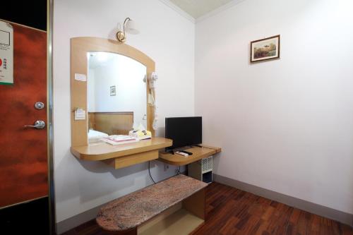 a room with a mirror and a desk with a computer at Long Shan Hotel in Jiaoxi