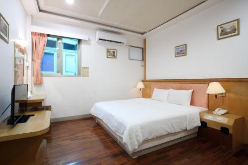 a bedroom with a white bed and a television at Long Shan Hotel in Jiaoxi