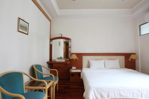 a hotel room with a bed and two chairs at Long Shan Hotel in Jiaoxi