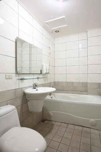 a bathroom with a tub and a sink and a toilet at Long Shan Hotel in Jiaoxi