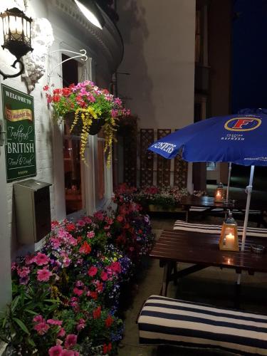 a patio with a table and flowers and an umbrella at Waterfront Hotel in Deal