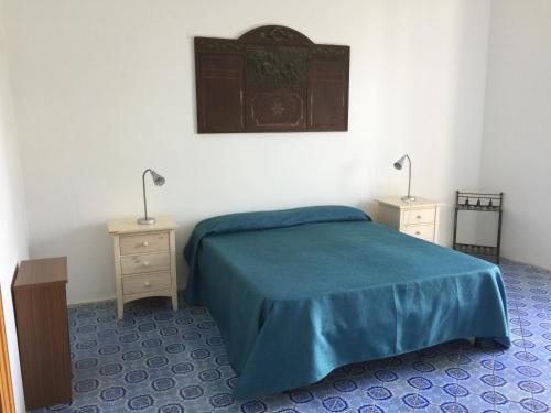 een slaapkamer met een blauw bed en 2 nachtkastjes bij Casa Galletta in Stromboli