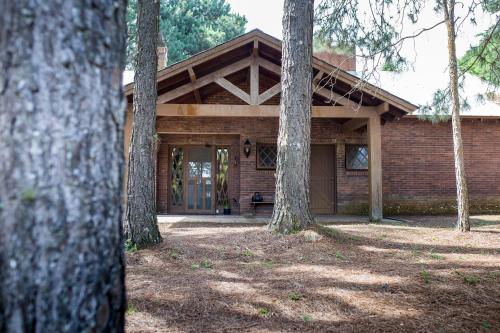 a wooden house with a porch and two trees at OM B&B + Spa in Viamão