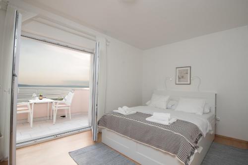 ein weißes Schlafzimmer mit einem Bett und einem Balkon in der Unterkunft Villa Mara Smokvica Krmpotska in Klenovica