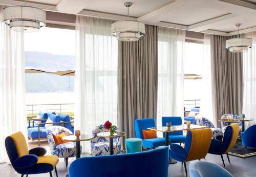 a restaurant with blue chairs and tables and large windows at Hôtel Les Roches Blanches Cassis in Cassis