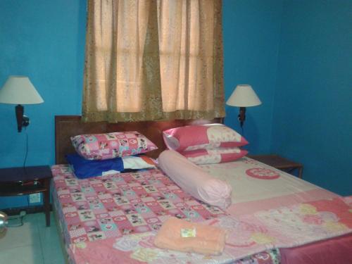 a bedroom with a bed with pink sheets and pillows at Seri Lagenda Apartment in Kuah