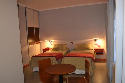 a hotel room with two beds and a table at EL Molle Hotel Boutique in Sarmiento
