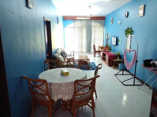 a room with a table and chairs and a blue wall at Seri Lagenda Apartment in Kuah