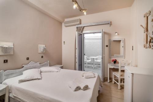 a white bedroom with two beds and a desk at Amaryllis Hotel in Perissa