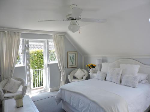 a white bedroom with a white bed and two chairs at Riverlea in Cape Town