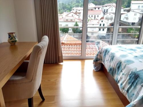 a bedroom with a desk and a bed and a large window at Casa D.Dinis in Vide