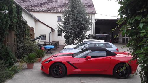 a red car parked next to two cars in a driveway at Gästezimmer Sommer Locktow in Locktow