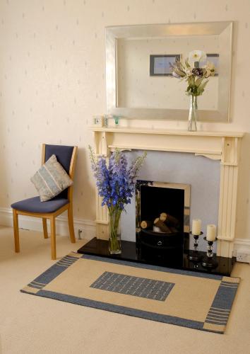 a living room with a fireplace and a vase of flowers at Thornbank House Offering Breakfast and with the use of Free Local Health Club in Windermere