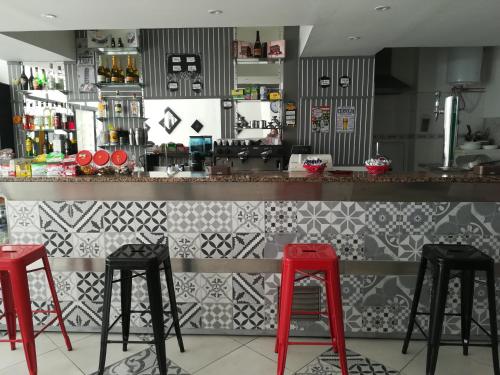 a bar with three red stools in a restaurant at Hotel Cristo Rei in Porto