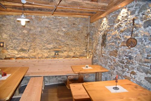 a restaurant with wooden tables and a stone wall at Residence Blumenthalerhof in Lagundo