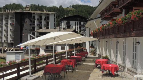 a row of tables with red chairs and an umbrella at Hotel La Meridiana in Madesimo