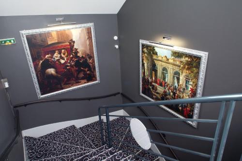 a staircase with two large paintings on the wall at Best Western Blois Château in Blois