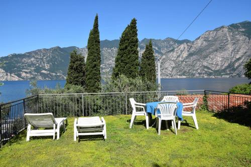 a group of chairs and tables on a lawn with a lake at Hotel Vela Azzurra in Malcesine