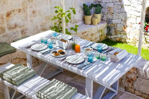 a white table with plates of food on it at Hermanas Relais - trulli luxury in Alberobello