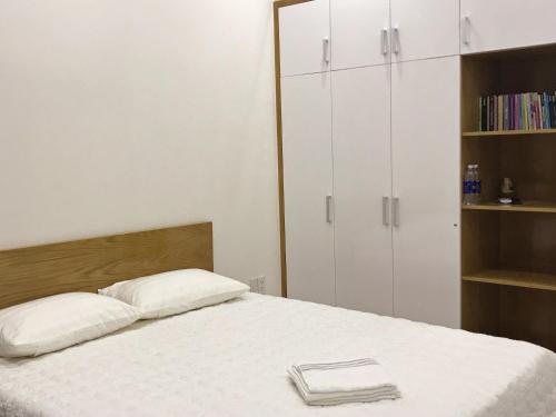 a bedroom with a bed with white cabinets and a book shelf at 91 Homestay, Cafe, Bonsai in Vung Tau