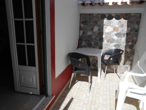 Pokój z dwoma czarnymi krzesłami i stołem w obiekcie Sol Dourado w mieście Zambujeira do Mar